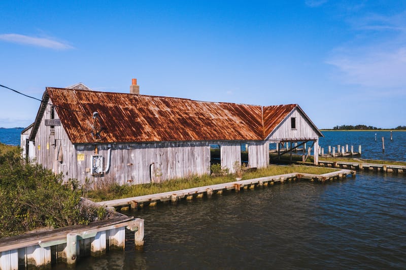 This is an aerial of an abandoned oyster house along the shores of Chincoteague Bay on George Island Landing, a declined oyster, clam, and crab fishing village in Maryland